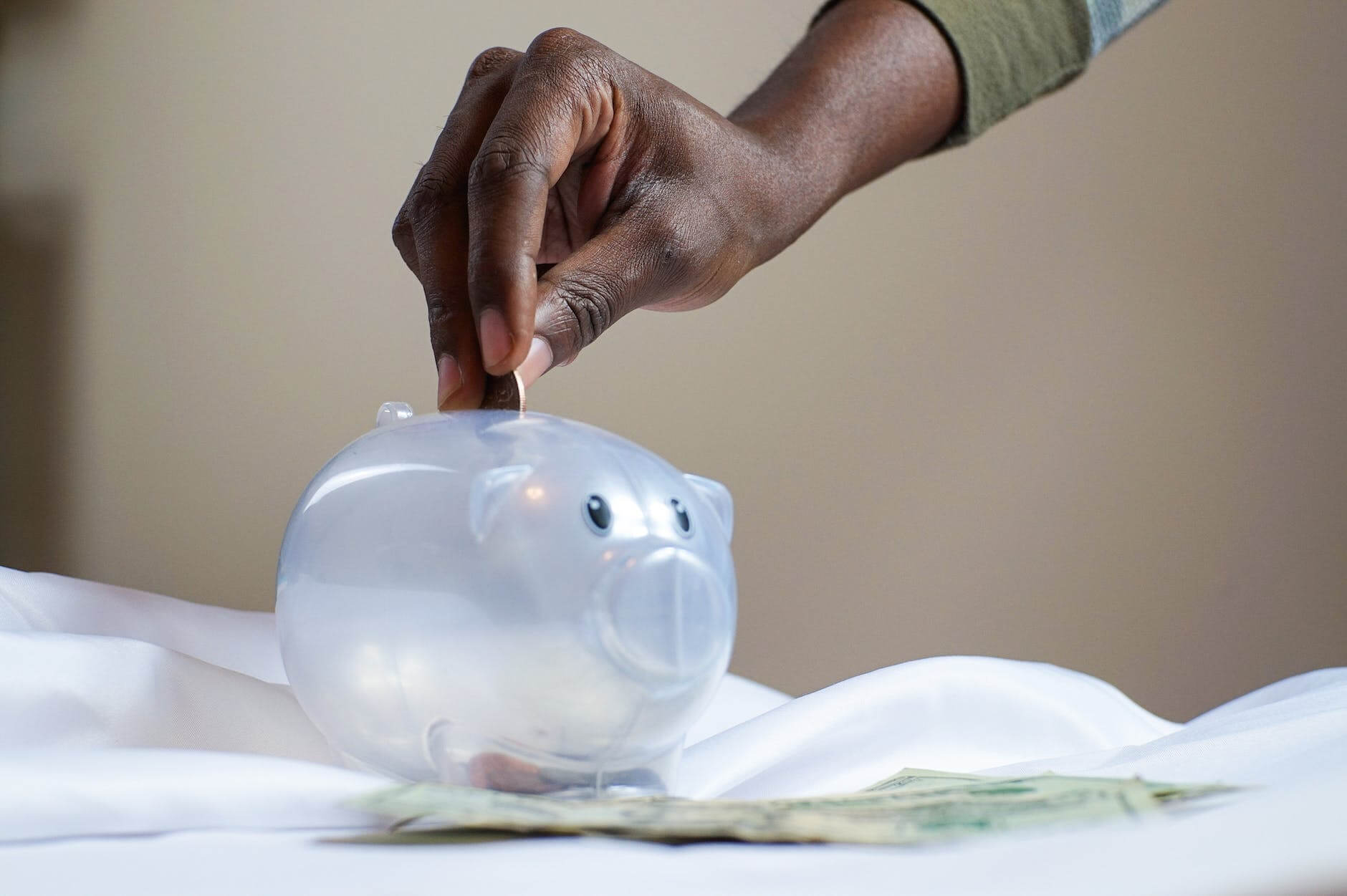 hand inserting coin into a piggy bank